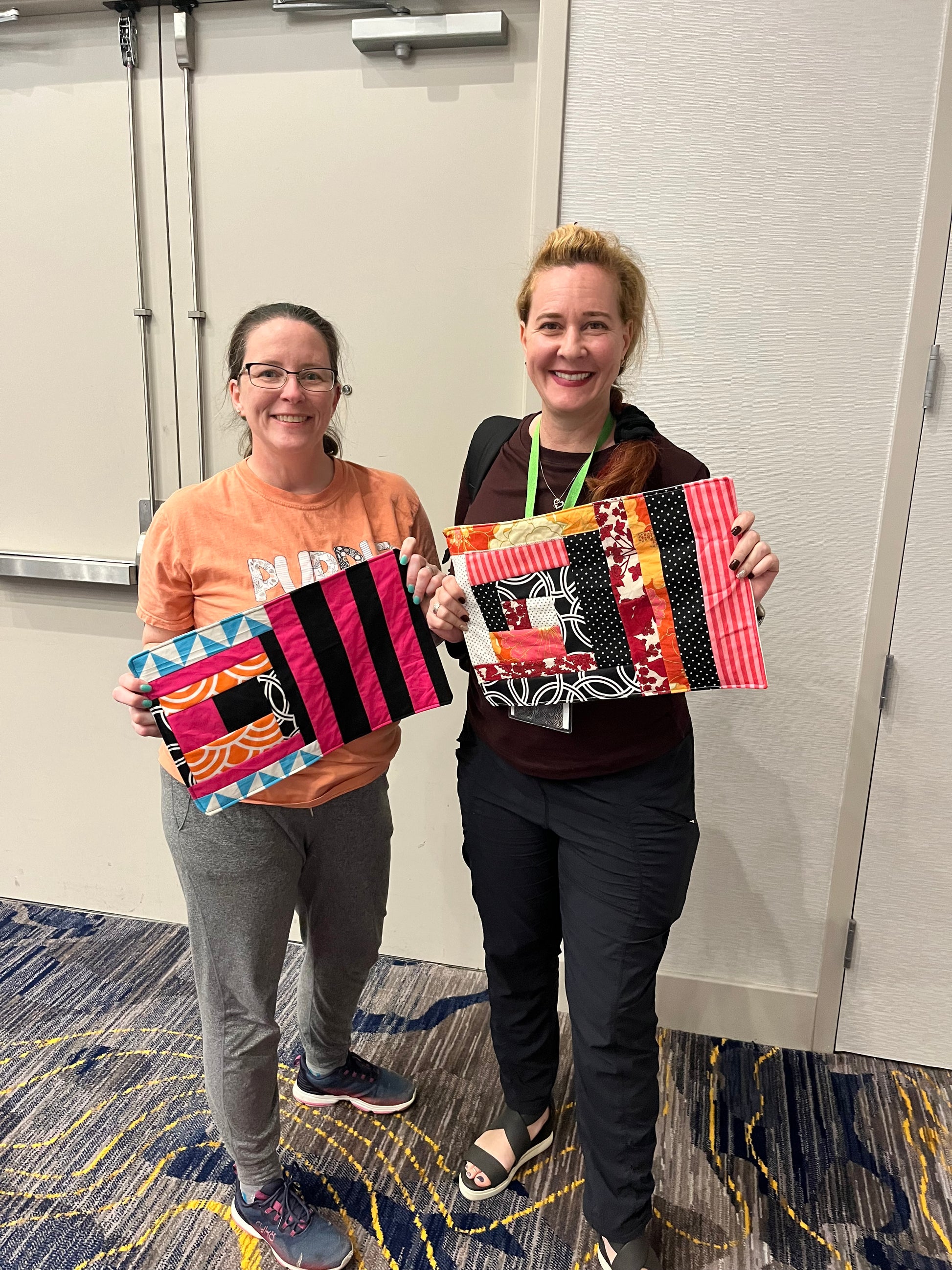two smiling women holding finished quilt as you go placemats
