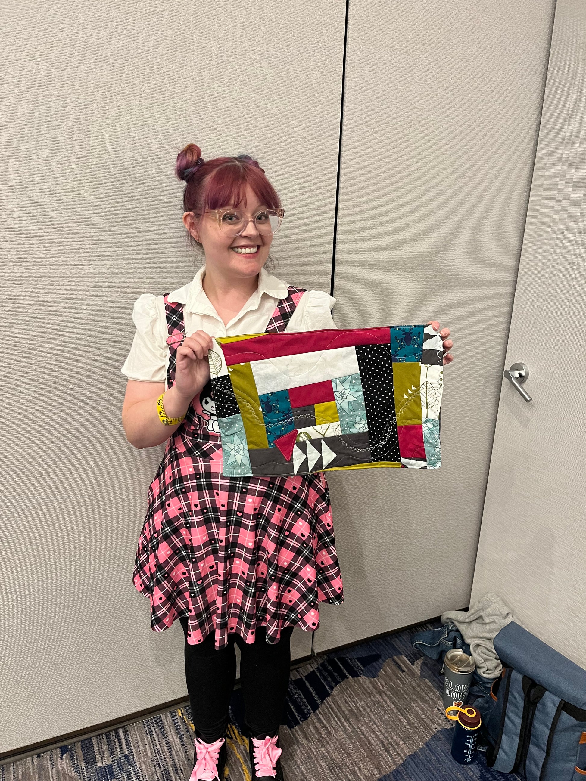 smiling woman with glasses holding a finished quilt as you go placemat